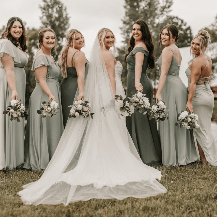 bride and all her bridesmaids looking back at camera with bouquets by hips